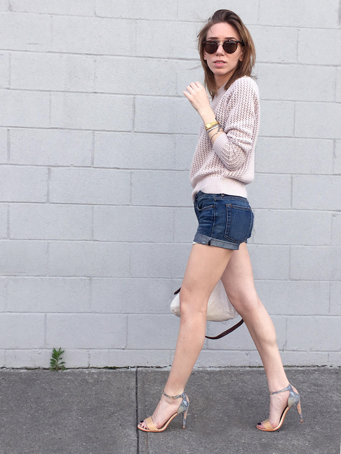 Sideview of pink sweater with denim shorts and heels