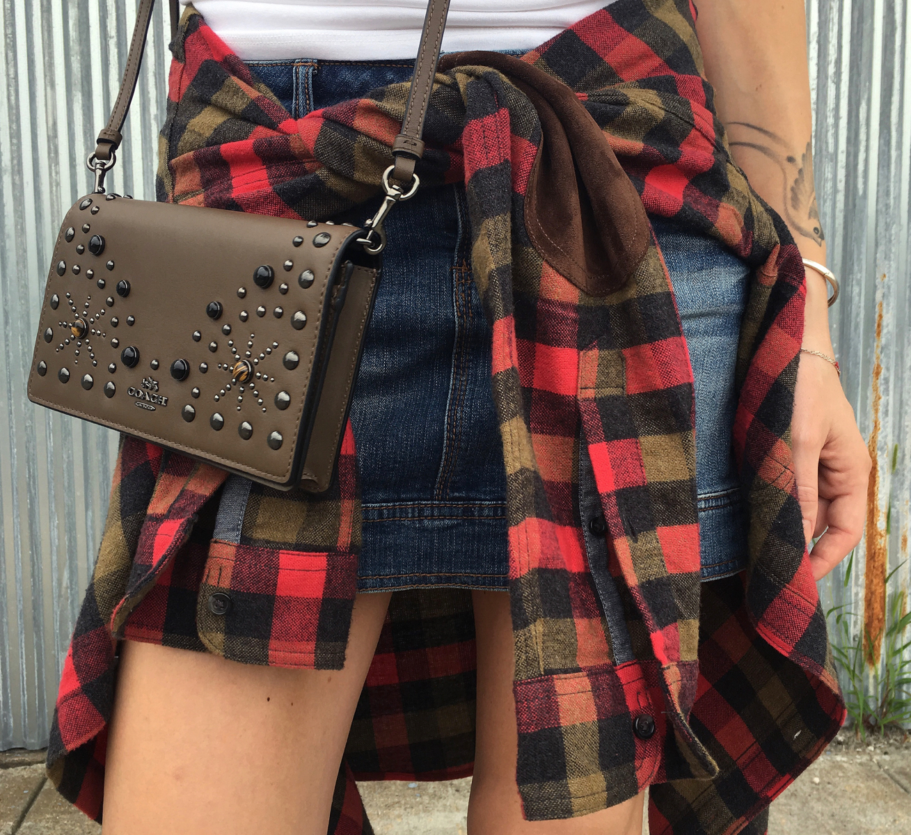 Coach studded bag with denim skirt and red flannel