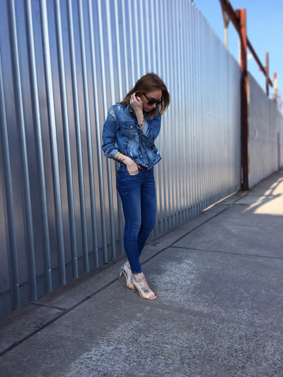Girl wearing denim jacket and denim jeans posing on the sidewalk