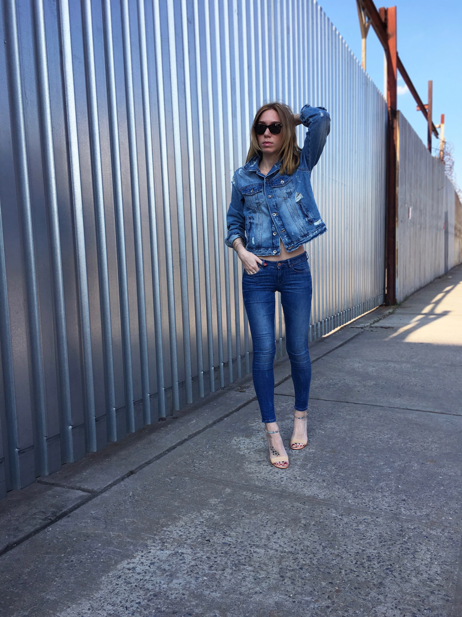 Girl wearing denim jacket and denim jeans outfit posing on the sidewalk