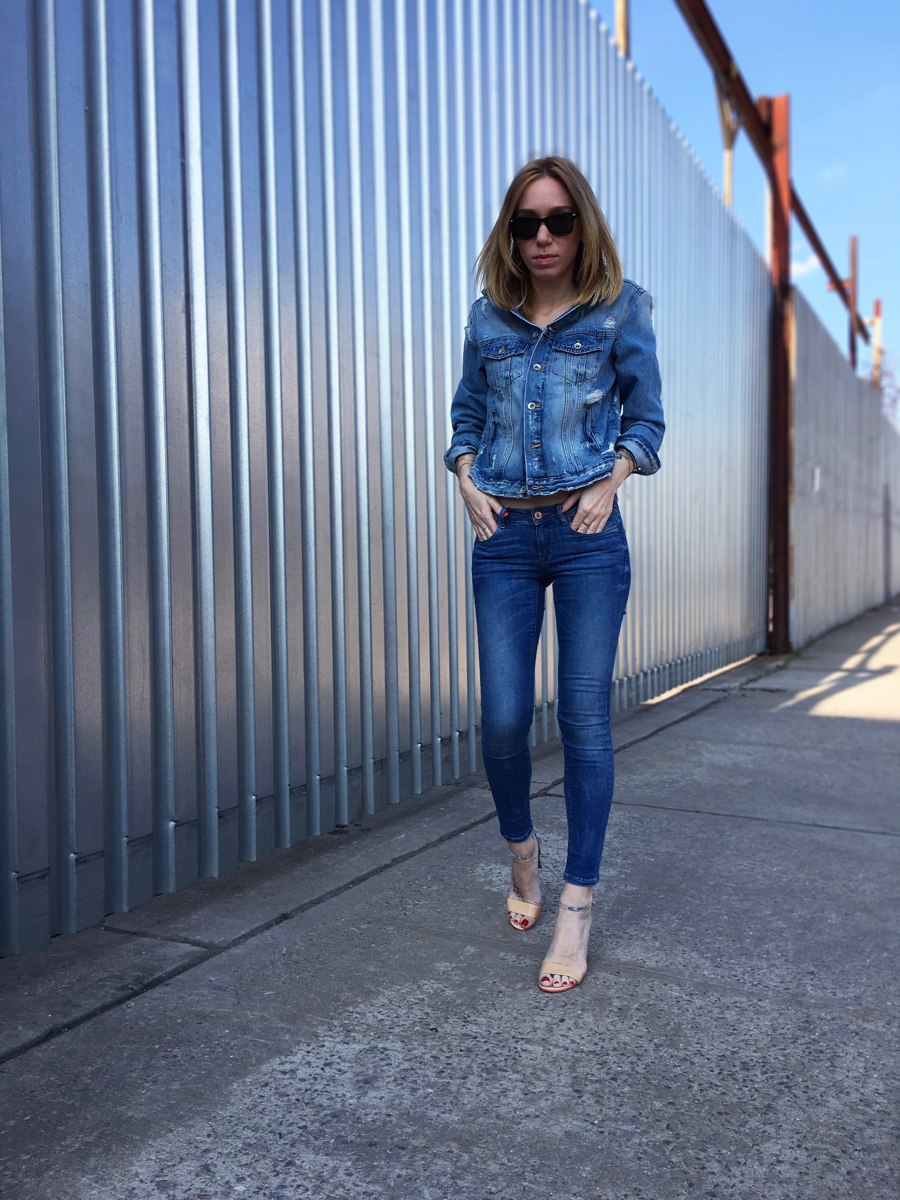 Girl posing in denim jacket and jeans on the sidewalk