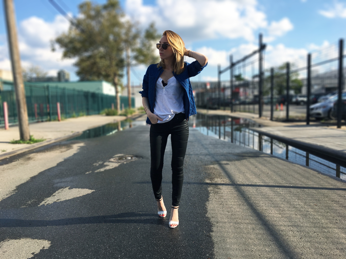 Woman wearing black jeans with white top and navy shirt posing in street