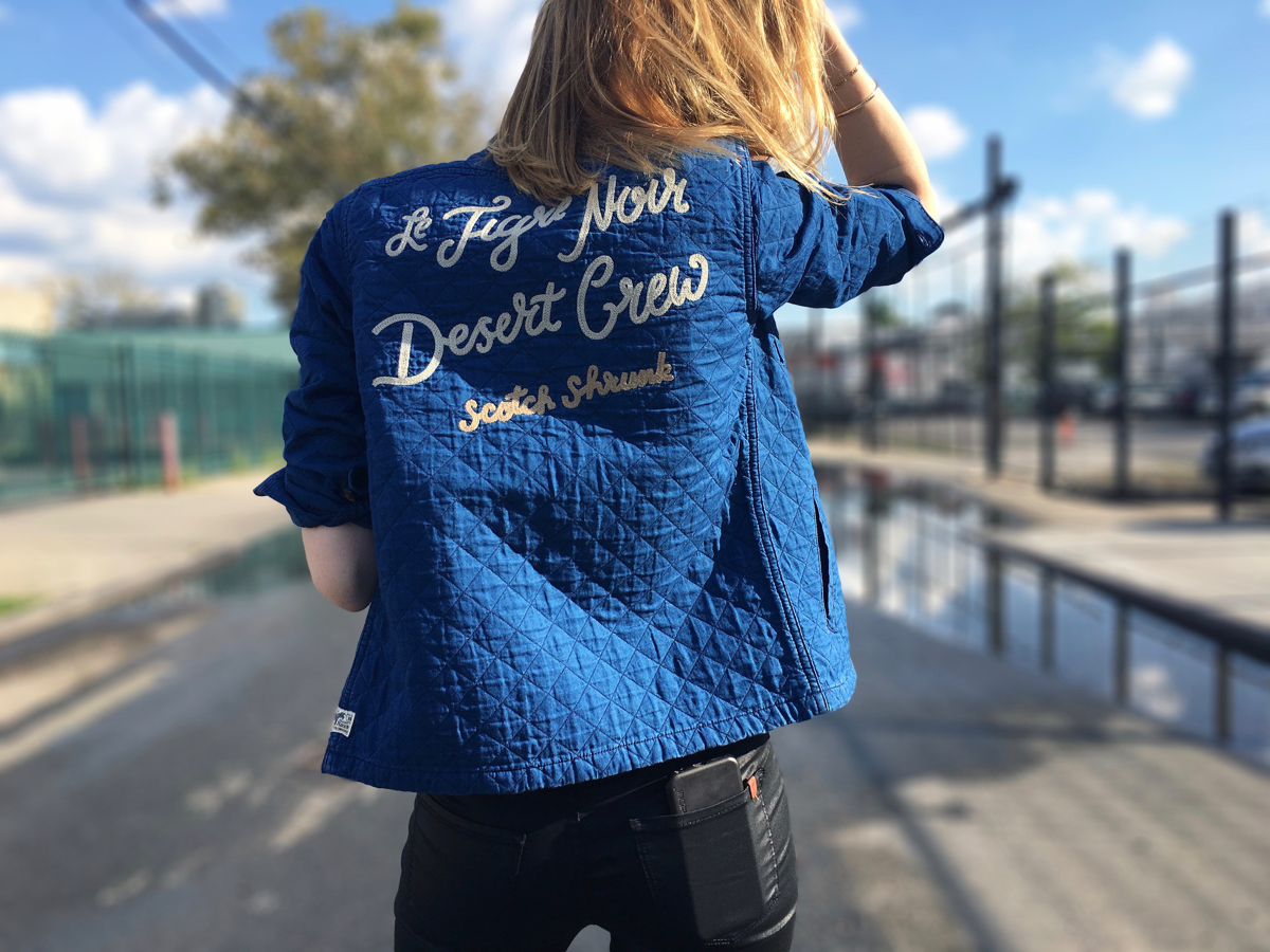 Woman wearing embroidered navy shirt in street zoomed in back view