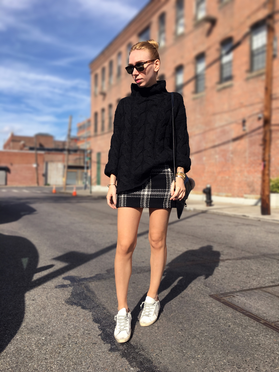 Woman wearing black sweater and miniskirt posing on street