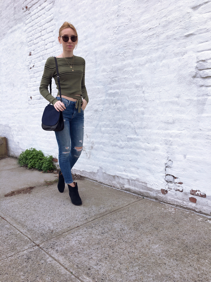 Woman walking wearing jeans and green cropped sweater