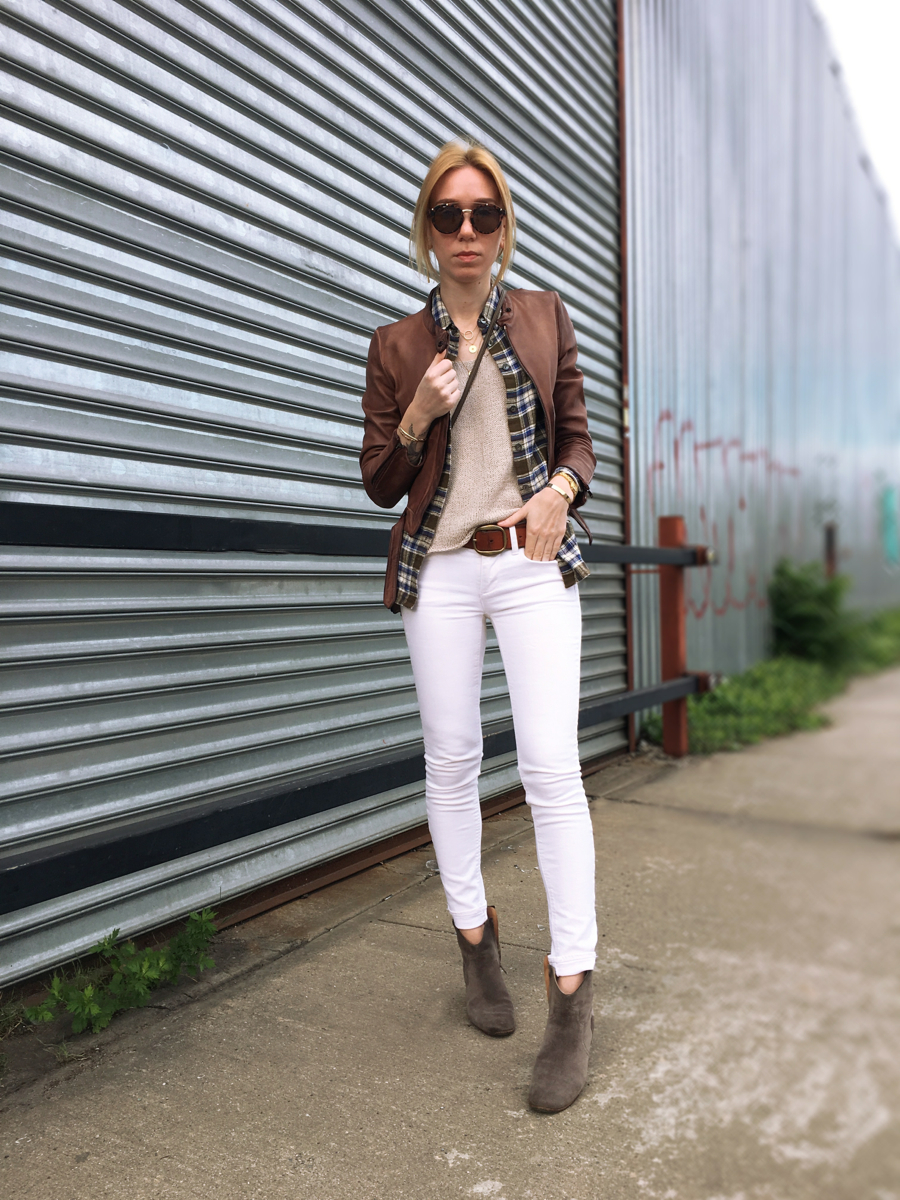 Woman posing forwards wearing white jeans and brown leather jacket