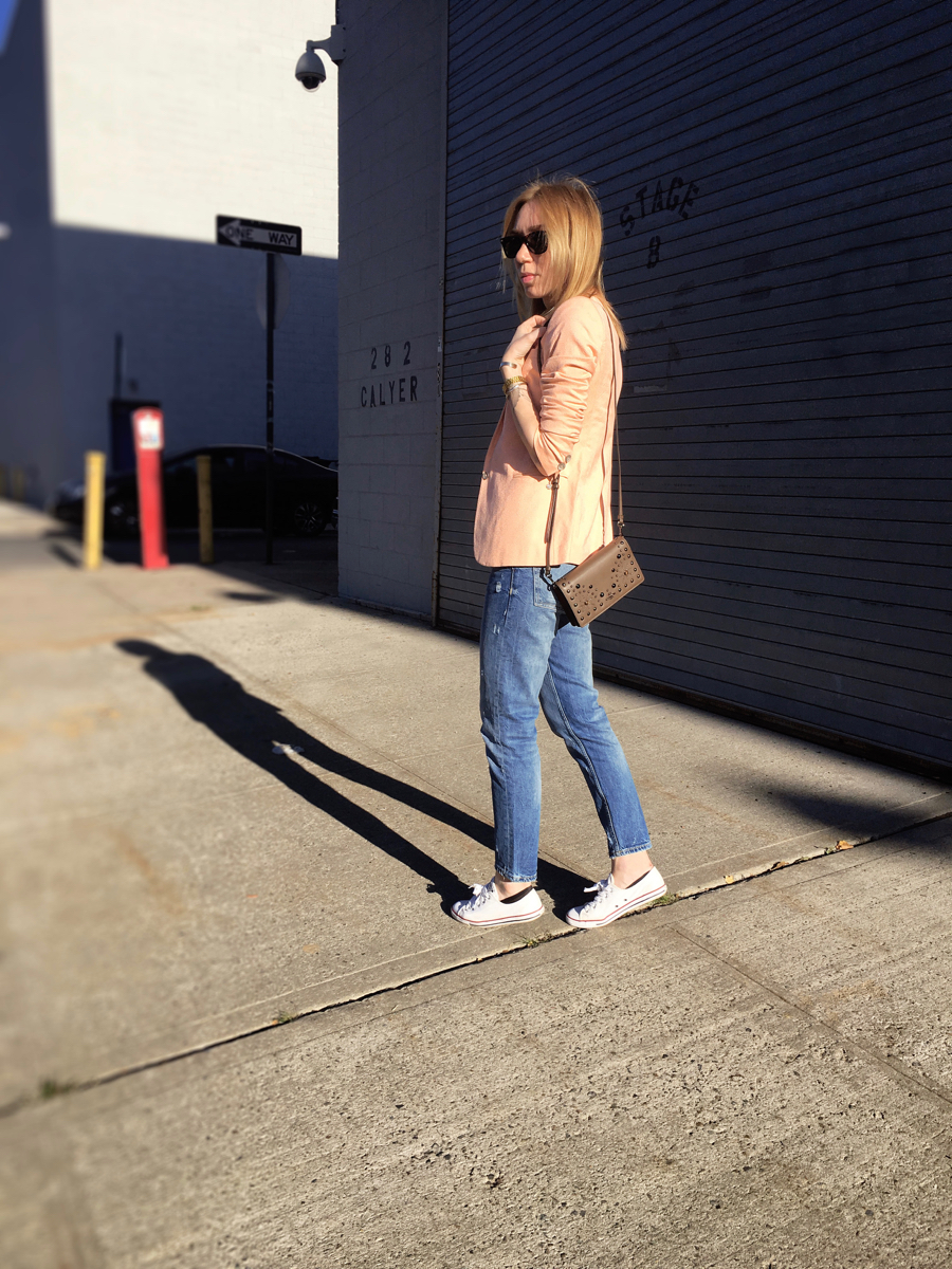 Woman posing sideways wearing neon colored blazer and jeans outfit