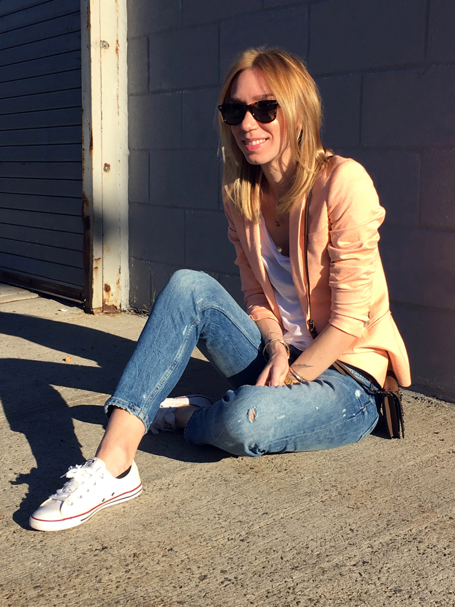 Woman sitting on sidewalk wearing neon colored blazer outfit