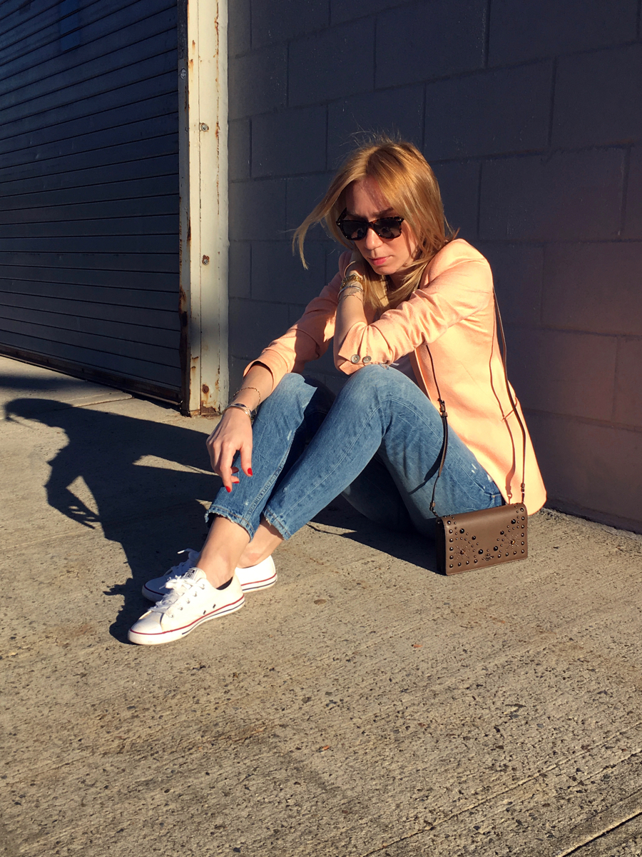 Woman sittong on sidewalk wearing neon colored blazer outfit