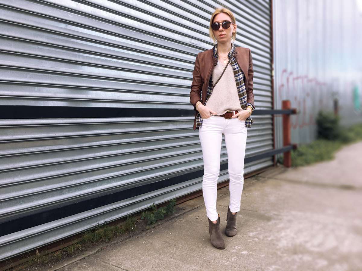 Woman posing forwards wearing white jeans and a leather jacket