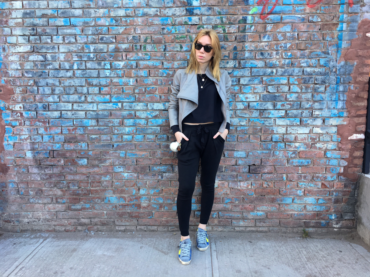 Woman posing against brick wall wearing Golden Goose sneakers