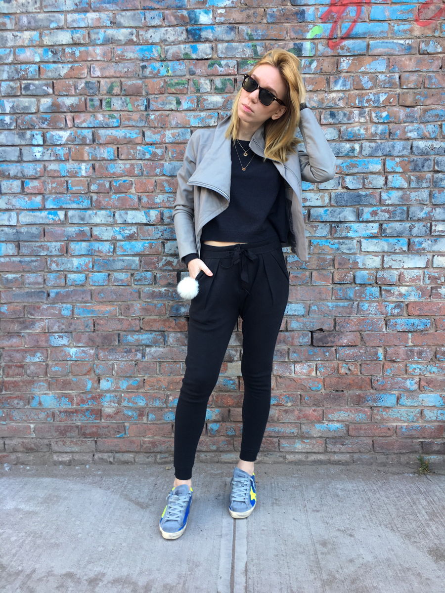 Woman posing against brick wall wearing Golden Goose sneakers