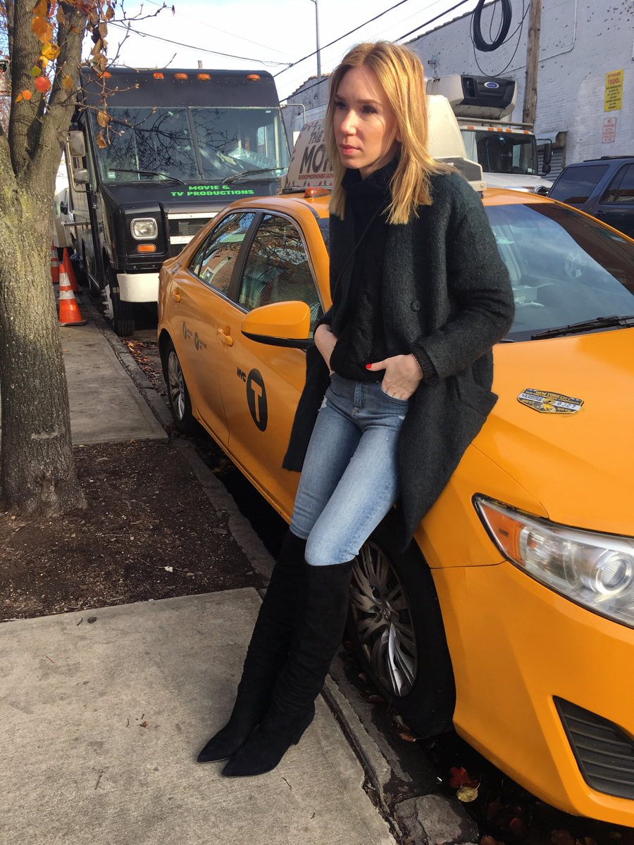 Woman sitting on yellow cab wearing outfit and black over the knee boots