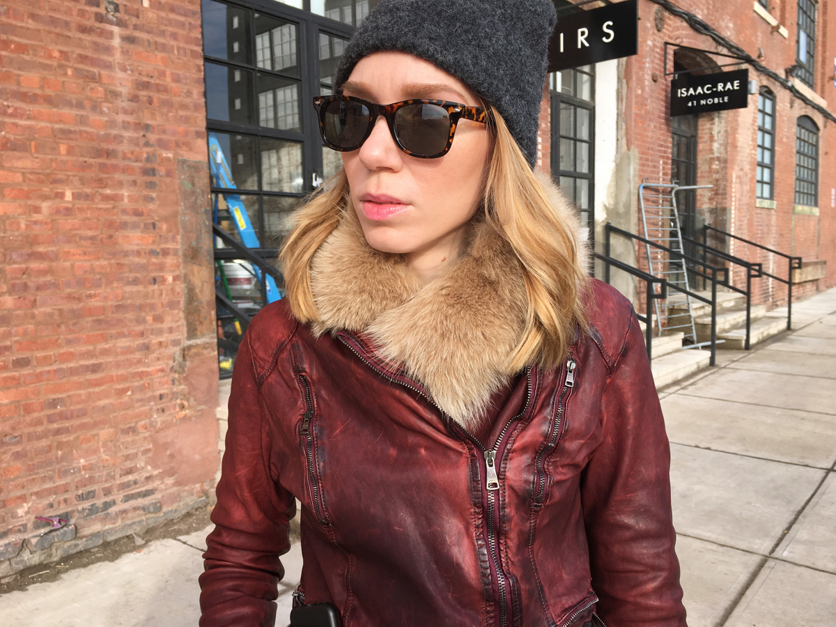 Woman looking sideways wearing red leather jacket and hat
