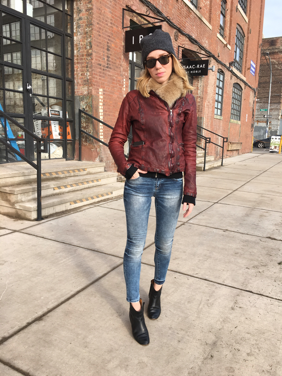Woman posing wearing red leather jacket and jeans with booties