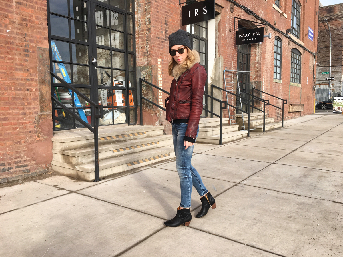 Woman standing sideways wearing jeans and leather jacket