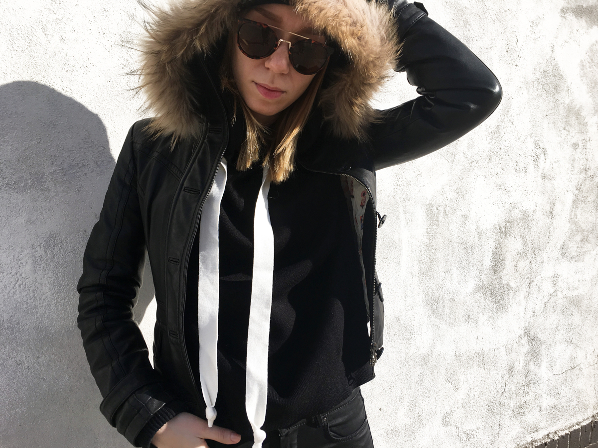 Woman wearing black hoodie and leather jacket posing