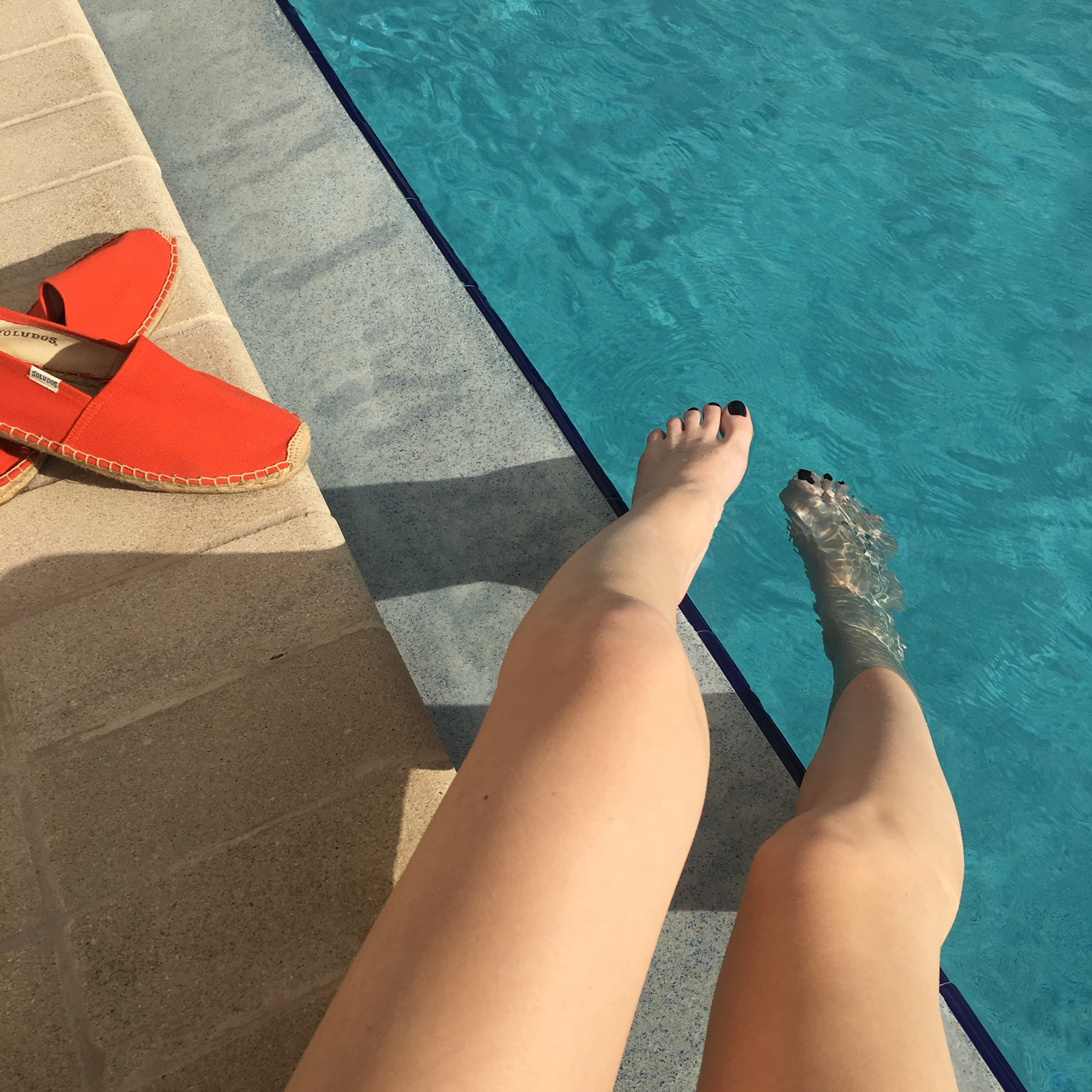 Legs dipped by a poolside
