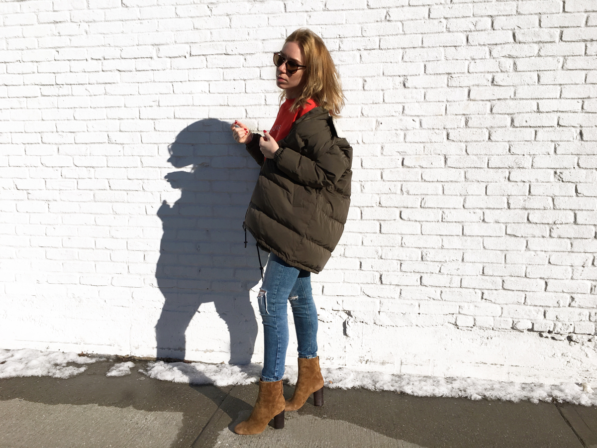 Woman posing sideways against white brick wall