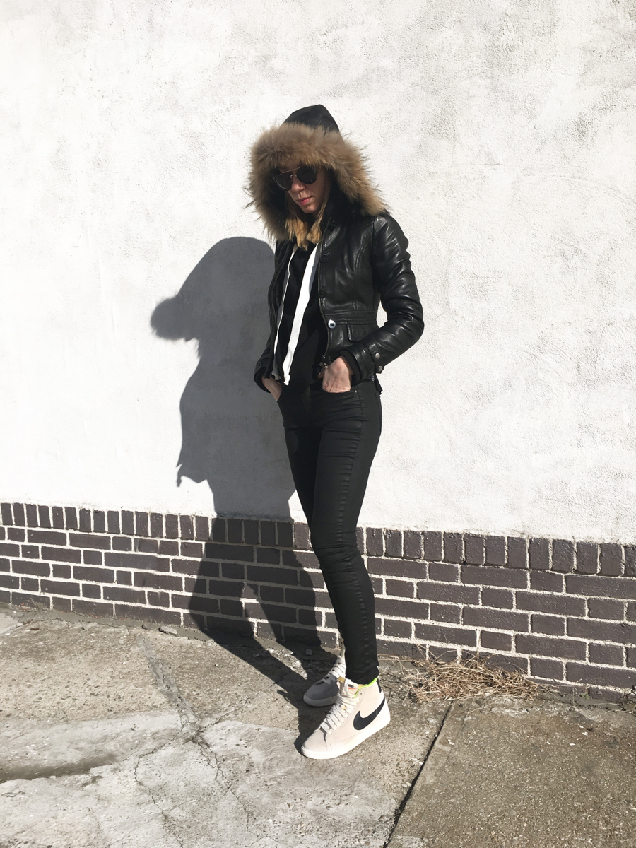Woman posing in all black outfit with grey sneakers