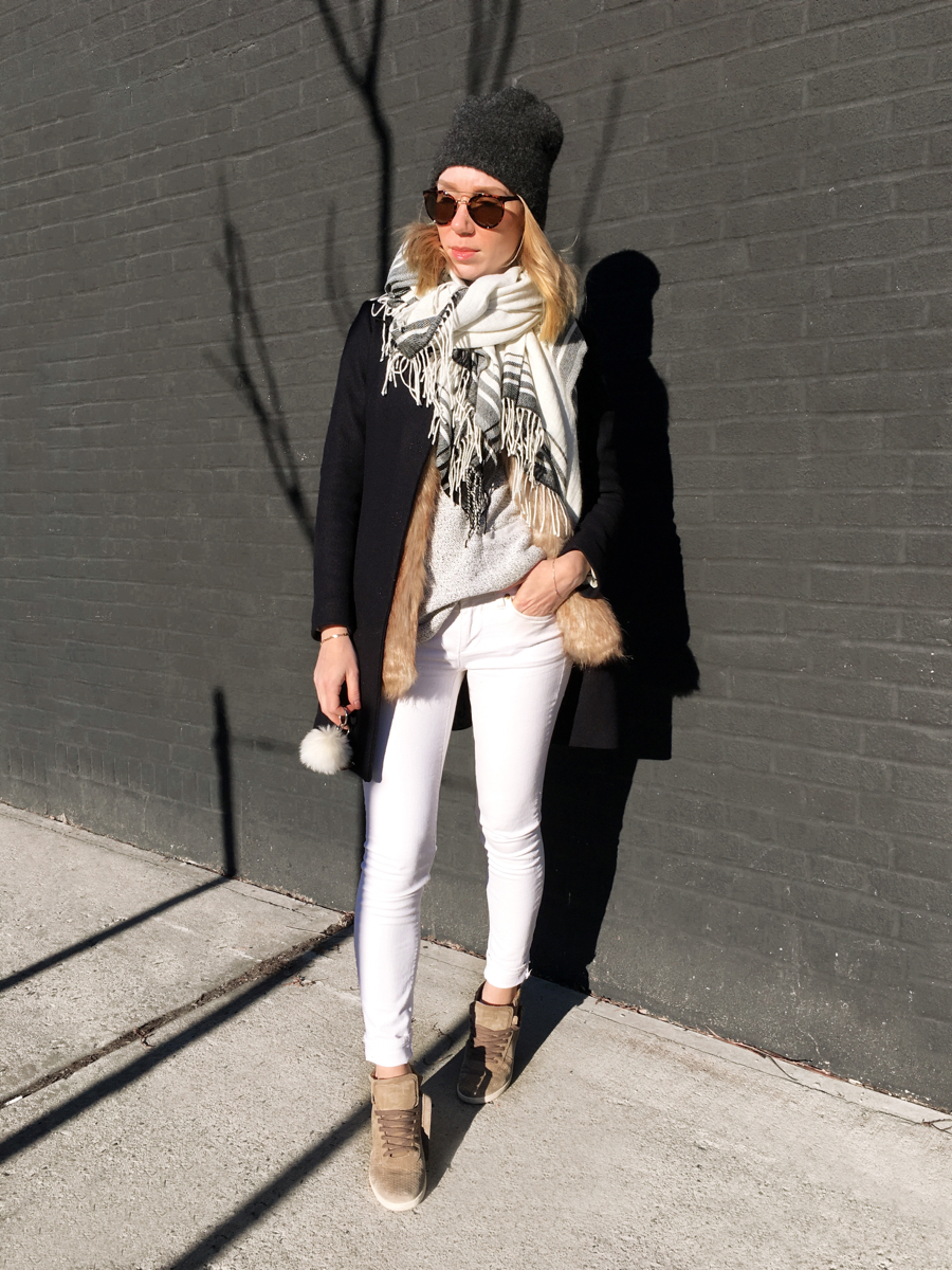 Woman posing in white jeans and navy coat