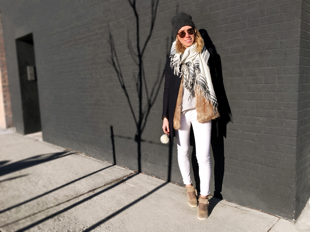 Woman wearing white jeans posing against brick wall