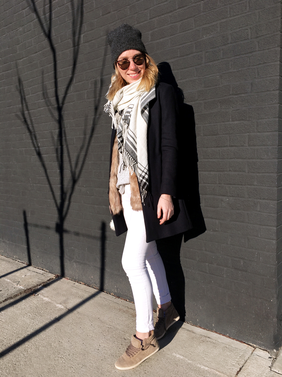 Woman posing in white jeans with fur vest and navy coat