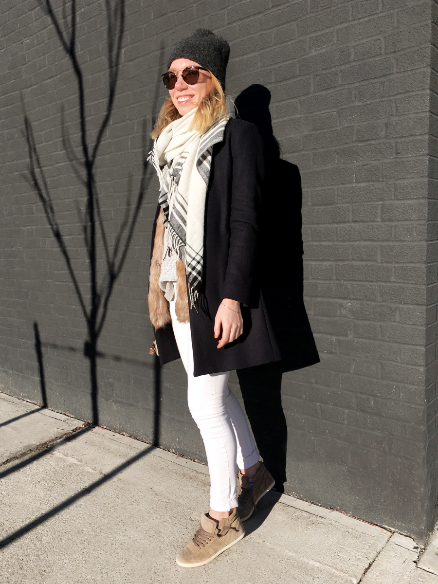 Woman posing against white jeans and navy coat