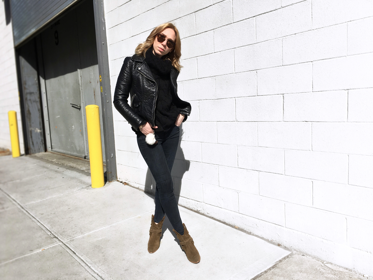 Woman posing in black leather jacket with dark sweater and jeans