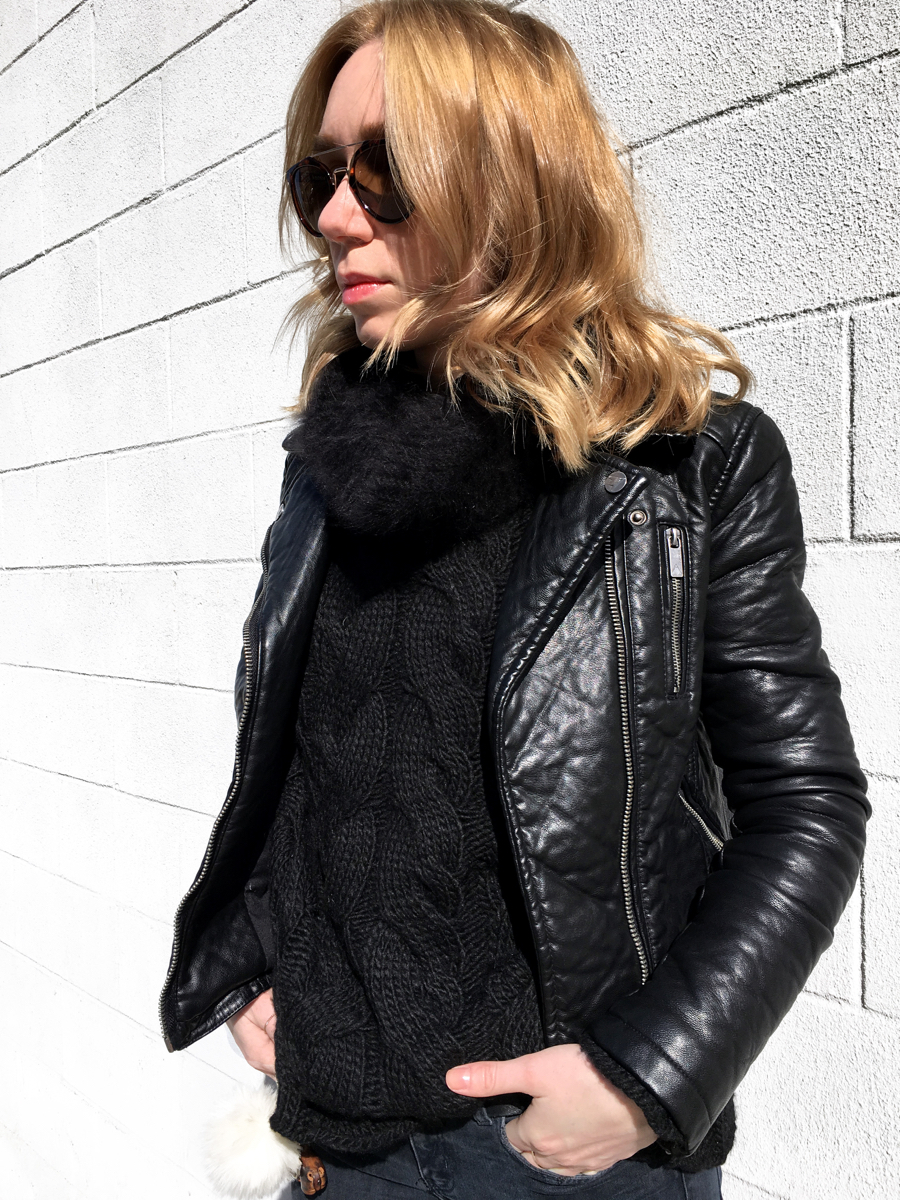 Side detail shot of woman wearing black sweater with leather jacket