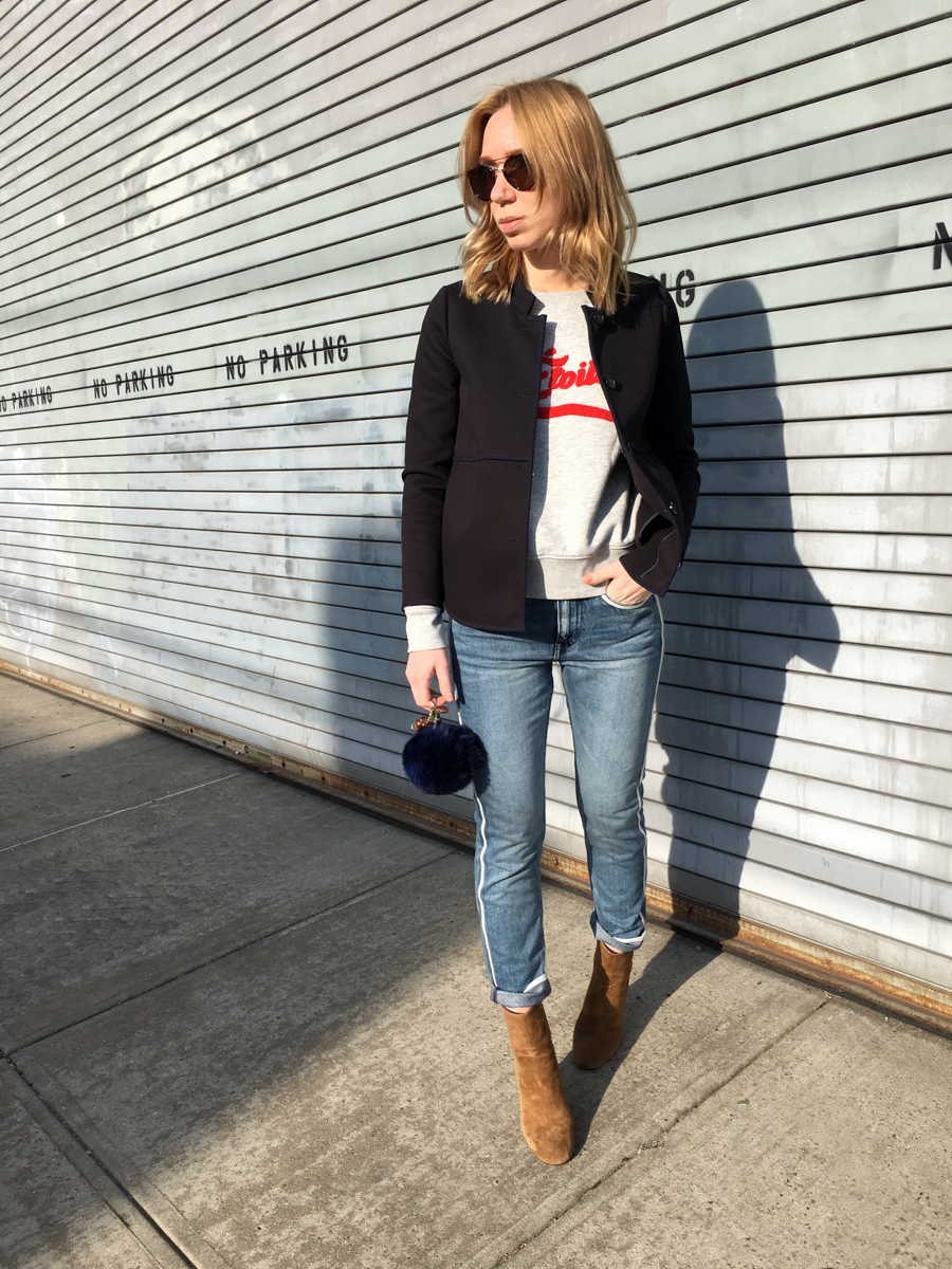Woman posing sideways wearing navy coat with denim