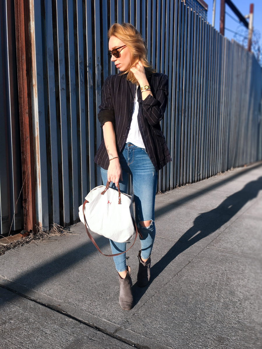 Woman posing in navy blazer with denim on the sidewalk