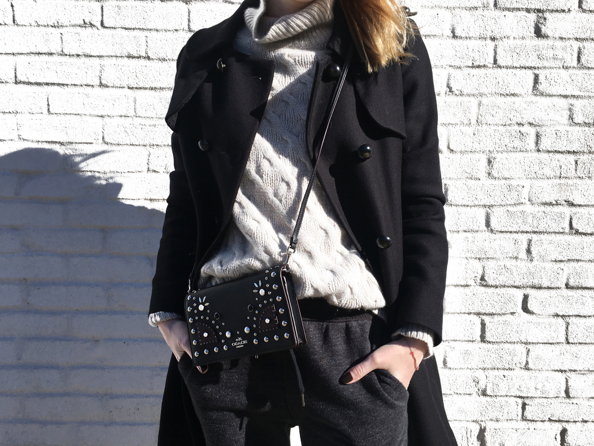 Detail shot of Coach bag with turtleneck and black coat