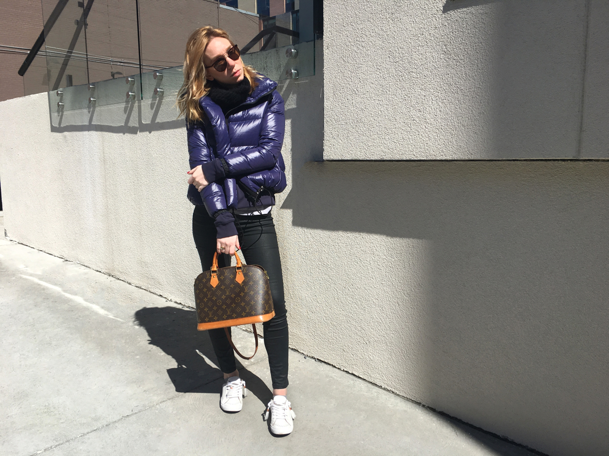 Woman posing in purple jacket and white sneakers
