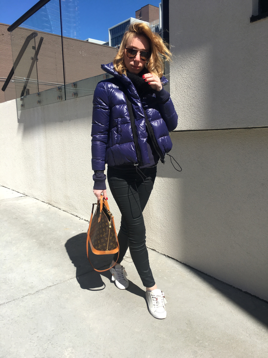Woman posing in purple jacket with black jeans and white sneakers