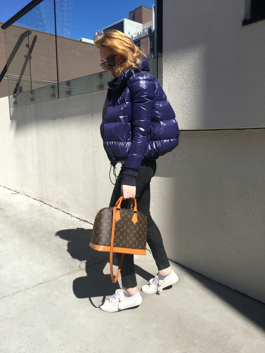 Woman posing in street style photo wearing white sneakers with black jeans and purple jacket