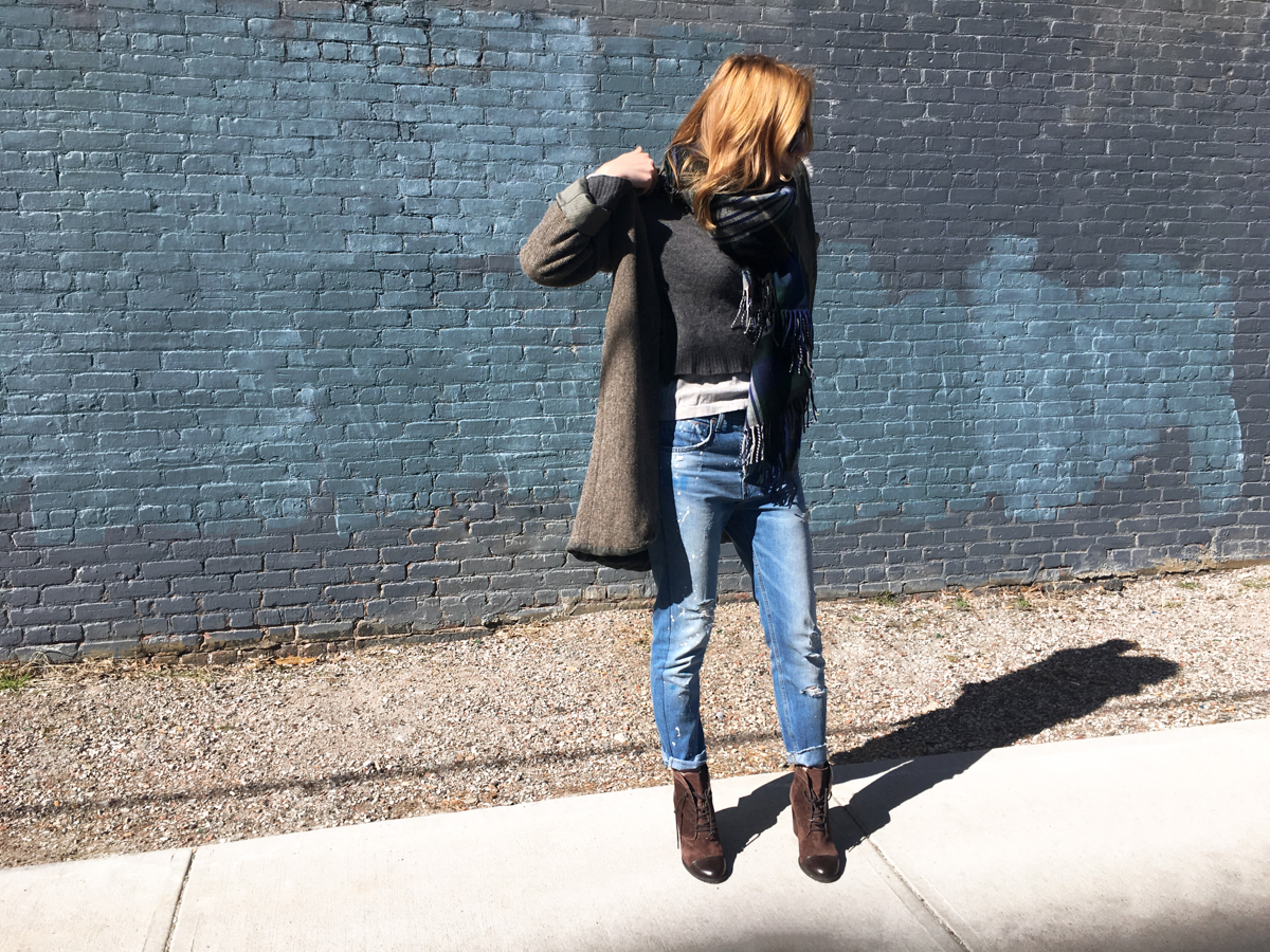 Woman putting coat on in street style photo