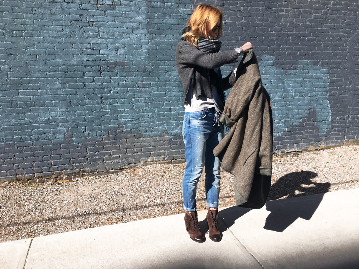 Woman holding coat posing in street style photo