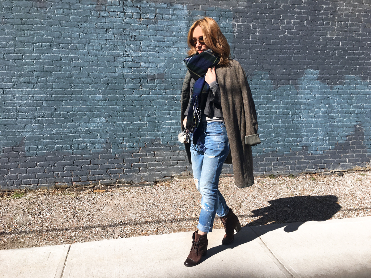 Woman posing in outfit against blue brick wall