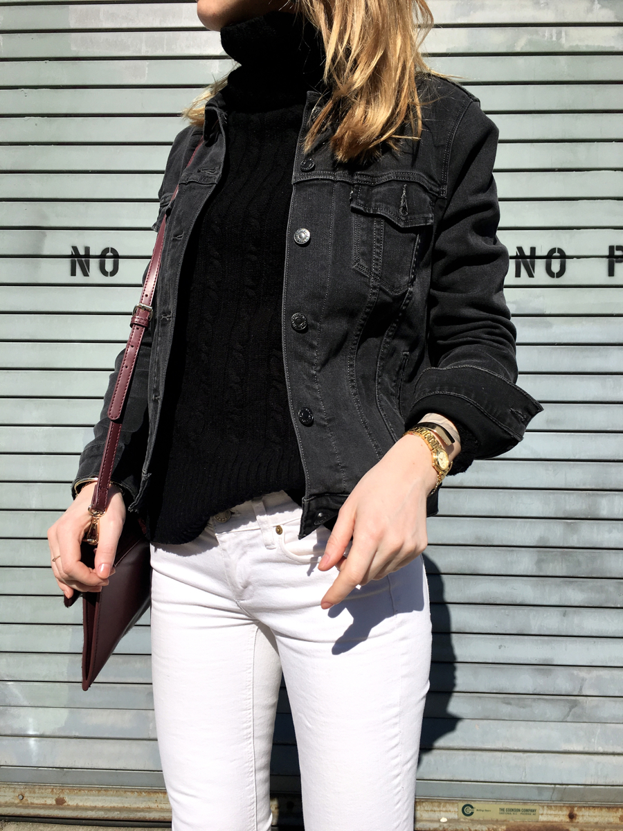 Side detail shot of grey denim jacket with black turtleneck and white jeans