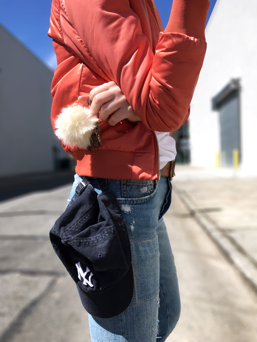 Side detail shot of pink bomber and jeans with Yankees cap
