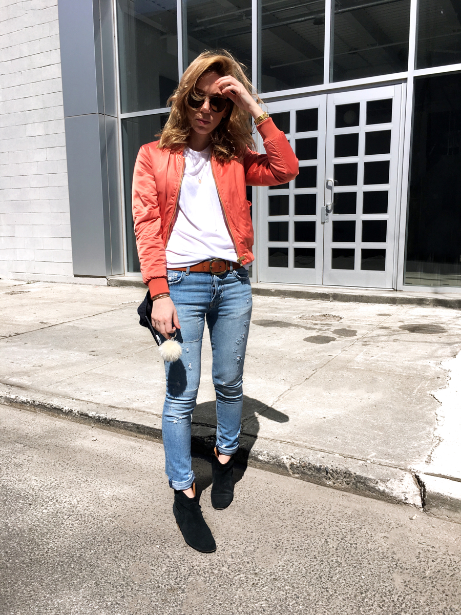 Woman posing wearing pink bomber with jeans 