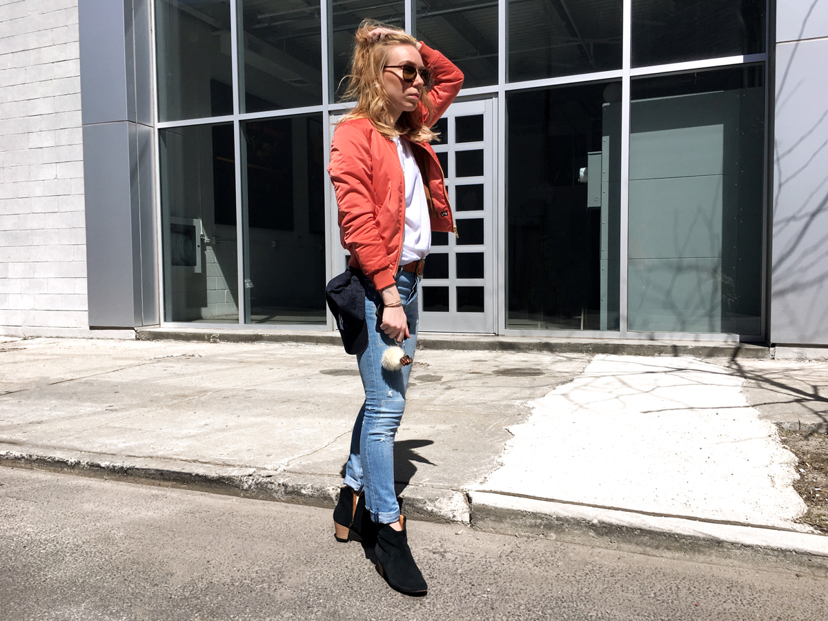 Woman with hand on head posing in pink bomber outfit