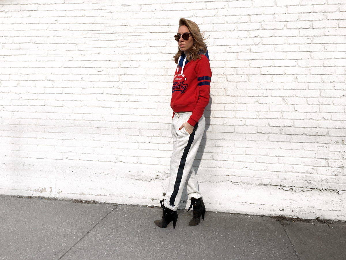 Woman posing sideways wearing grey sweats and red sweatshirt