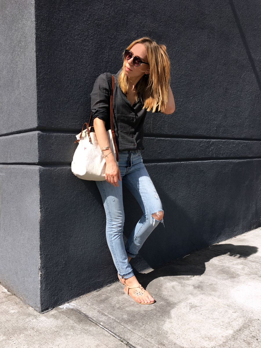 woman leaning against wall for outfit photo