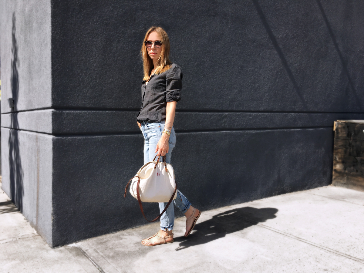 Woman standing against grey wall for street style photo