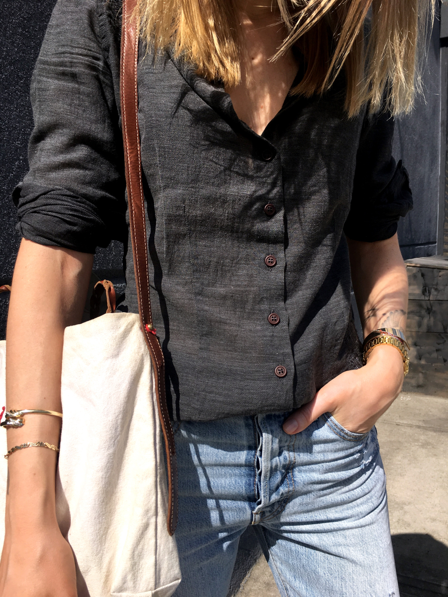 Side detail shot of grey button down shirt and beige tote