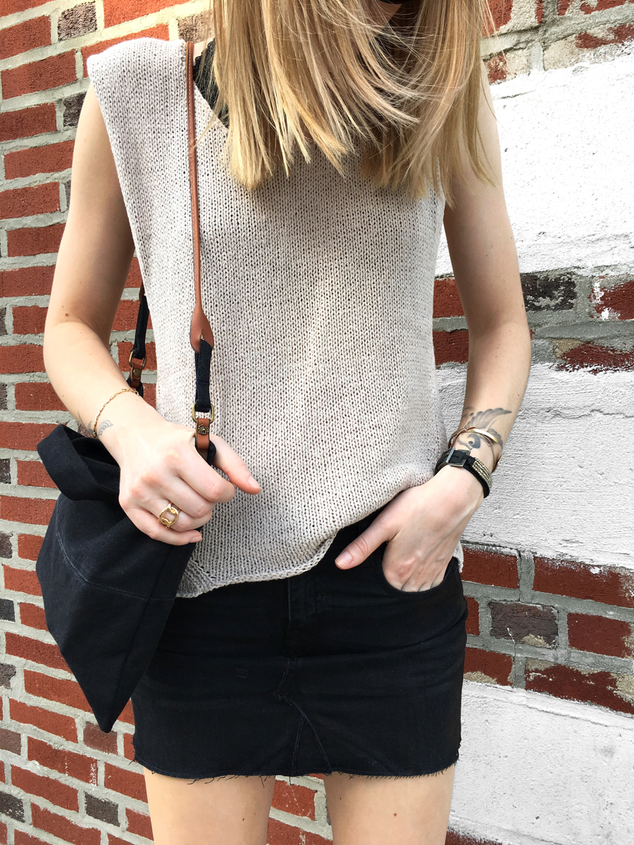 Detail shot of neutral colored knit and black skirt with bag