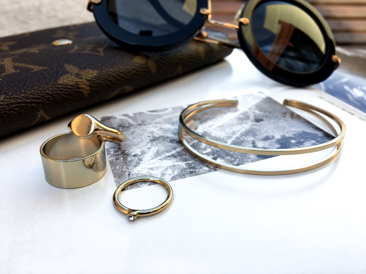 Jewelry placed on a magazine with sunglasses and wallet in background